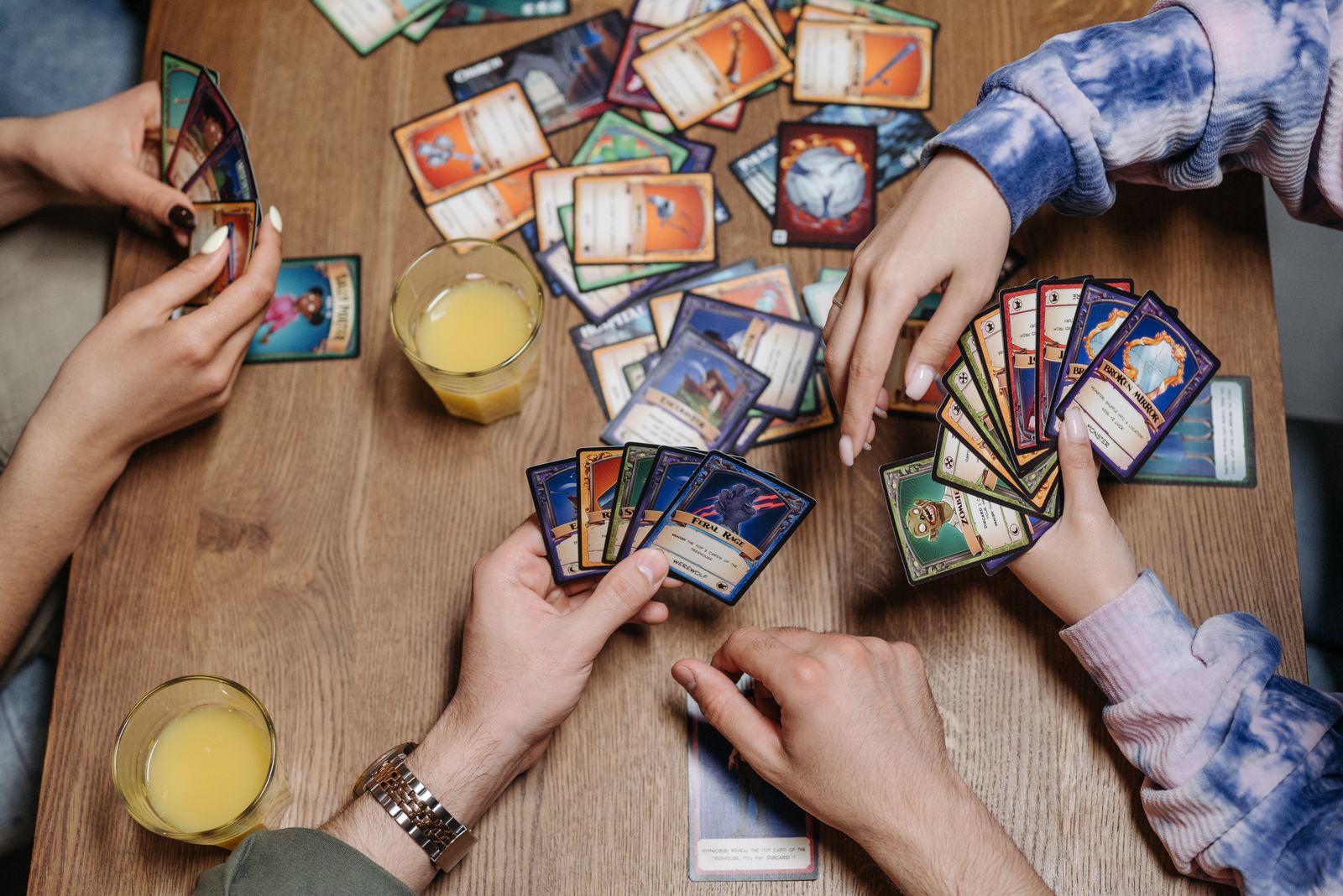 Friends playing a fantasy card game at a table, similar to a Gods Unchained match