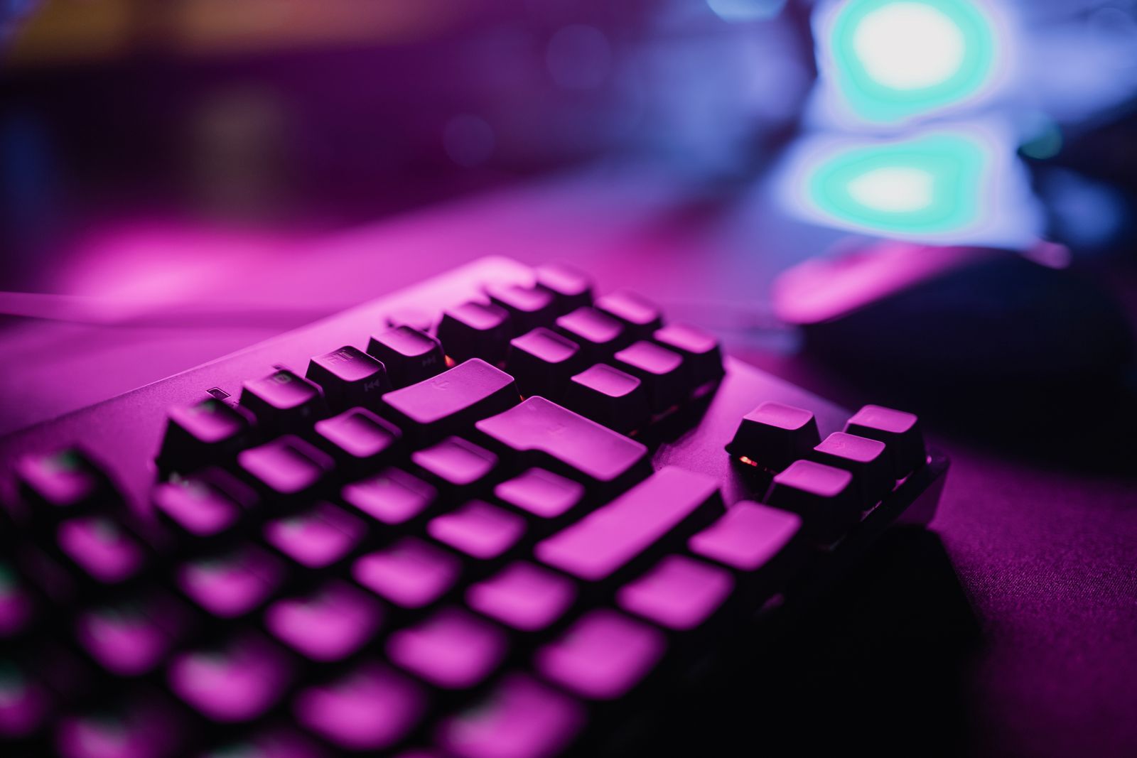 Backlit gaming keyboard glowing purple on a dark desk