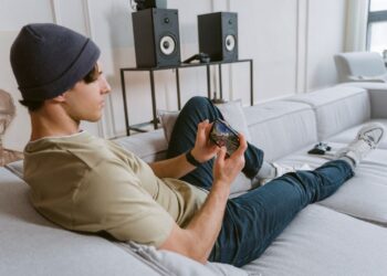 Young man playing a mobile game on a smartphone while sitting on a sofa