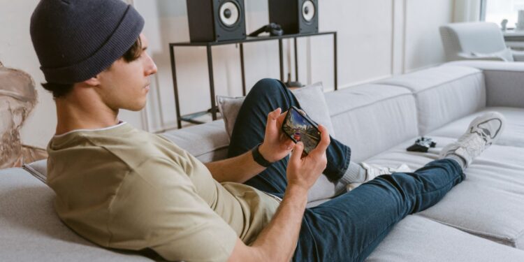 Young man playing a mobile game on a smartphone while sitting on a sofa