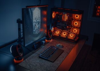 Gaming PC with orange-lit fans next to a monitor and keyboard on a desk
